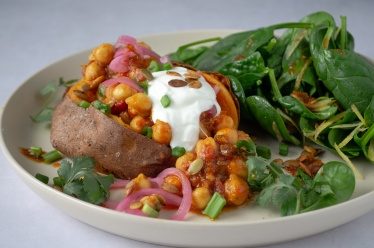 Baked sweet potato jackets topped with 15-Minute curry chickpea skillet stew with pink pickled onions and sour cream or dairy-free yogurt and roasted smoky pepitas. With a side of spinach salad. Easy, healthy, filling, plant-based, vegan recipe