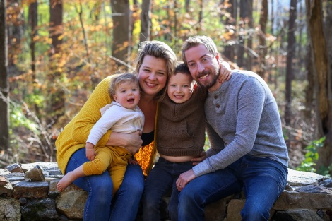 A family of four with a young boy and baby girl in the woods