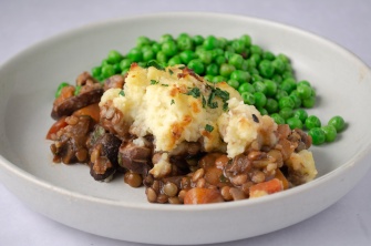 Cottage pie with lentils and vegetables and topped with mashed potatoes and a side of green peas. Easy, healthy, filling, plant-based, dairy-free, vegan recipe