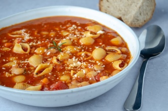 A bowl of pasta fagioli with pasta shells in a tomato sauce
