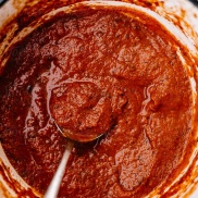 A pot of cooked red tomato sauce with a spoon