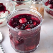 A jar of homemade mixed berry sauce with strawberries and blueberries
