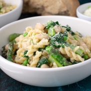 Bowl of pasta with asparagus, spinach, white beans, and parmesan cheese. Easy, healthy, filling, plant-based, vegan recipe