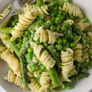 A bowl of pasta with basil pesto and asparagus and peas