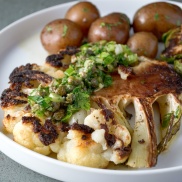 Roasted cauliflower steak, a vegan meal, topped with a parsley-lemon-caper drizzle