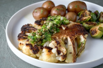 Roasted cauliflower steak, a vegan meal, topped with a parsley-lemon-caper drizzle