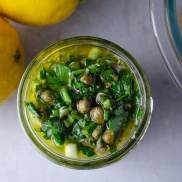 A jar lemon-herb dressing made with lemon, leafy herbs, and capers for topping cauliflower steaks and any other vegetables