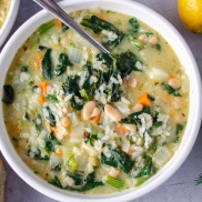 A bowl of creamy vegan rice soup flavored with lemon, white beans, and Spinach