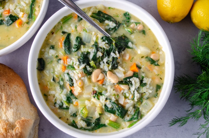 A bowl of creamy vegan rice soup flavored with lemon, white beans, and Spinach