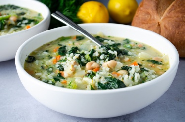 A bowl of creamy vegan rice soup flavored with lemon, white beans, and Spinach