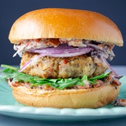 A homemade vegan bean burger filled with protein and flavored like pizza with sundried tomato mayo and arugula