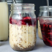 A jar of overnight oatmeal with chia seeds, nut butter, and homemade mixed berry sauce