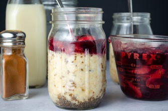A jar of overnight oatmeal with chia seeds, nut butter, and homemade mixed berry sauce
