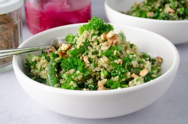 A warm green and grain salad made from quinoa and massaged kale and tossed with pesto