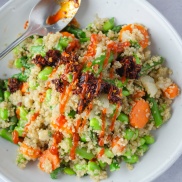 A quick skillet supper of quinoa and a mix of edamame, asparagus, and carrots, topped with chili crisp and sriracha