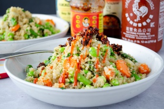 A quick skillet supper of quinoa and a mix of edamame, asparagus, and carrots, topped with chili crisp and sriracha