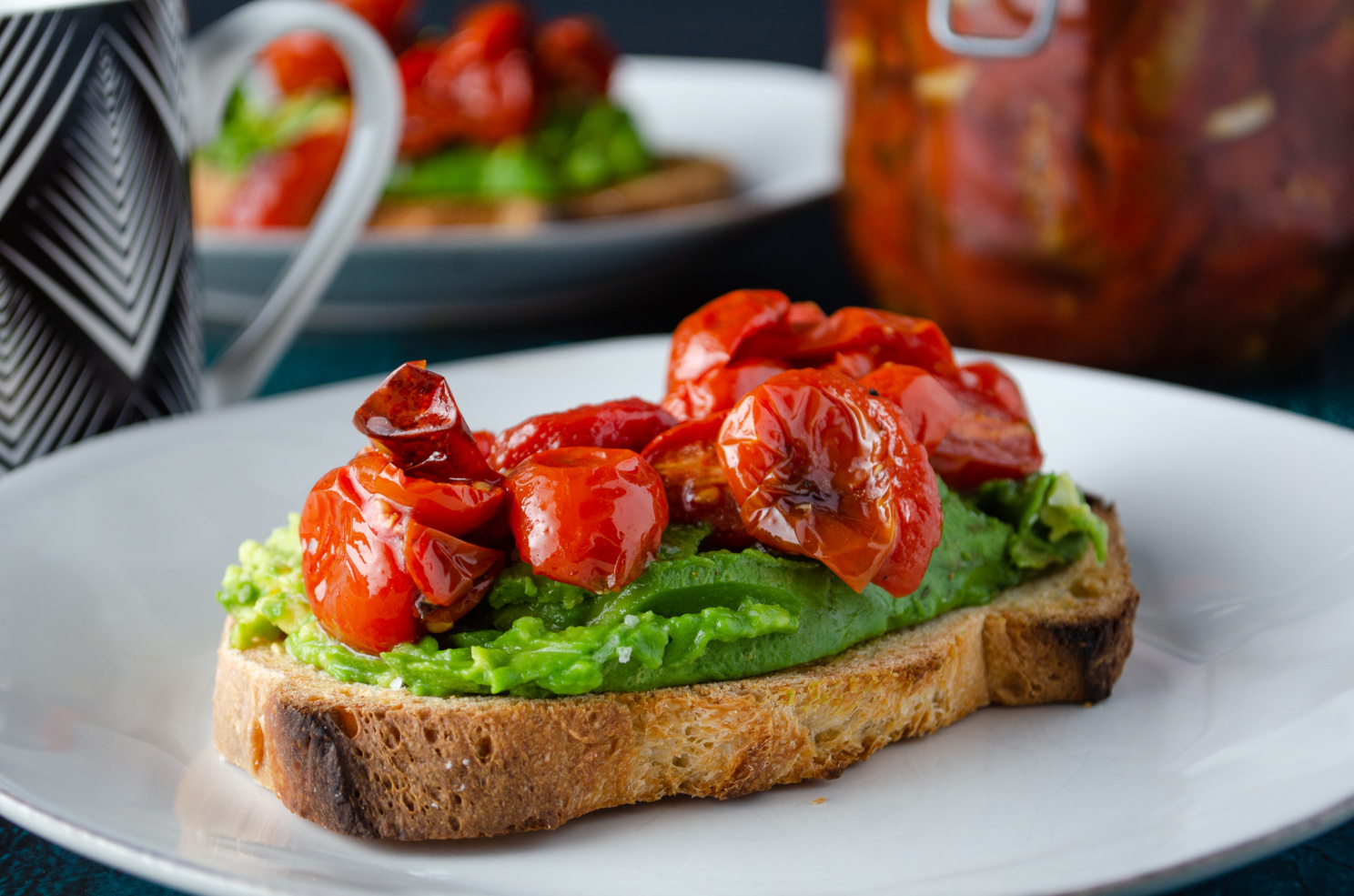 Hearty European style bread sliced and toasted with mashed avocado and roasted cherry tomato confit