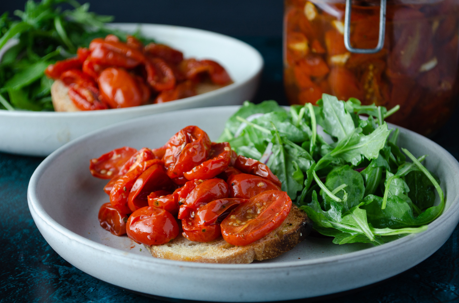 Rustic bread topped with a roasted cherry tomato confit with an arugula salad side