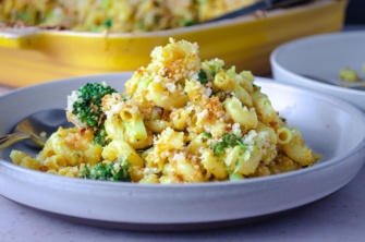 A plate of creamy, velvety, savory vegan, dairy-free, plant-rich mac and cheese with broccoli and breadcrumbs