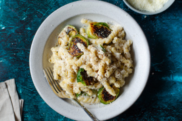 Dairy-free, vegan Alfredo sauce made with cauliflower rice over pasta and roasted brussel sprouts and topped with grated parmesan cheese. A creamy and hearty sauce that's great on pasta, pizza, veggies