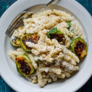 Dairy-free, vegan Alfredo sauce made with cauliflower rice over pasta and roasted brussel sprouts and topped with grated parmesan cheese. A creamy and hearty sauce that's great on pasta, pizza, veggies
