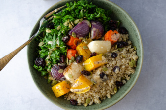 A fall or winter green and grain bowl made from hearty greens, cooked quinoa, and roasted vegetables drizzled with poppyseed dressing