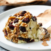 Festive plant-based "cheese" ball made from vegan, dairy-free cream cheese and coated with beautiful walnuts and dried cranberries