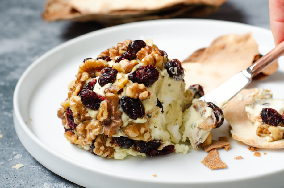 Festive plant-based "cheese" ball made from vegan, dairy-free cream cheese and coated with beautiful walnuts and dried cranberries