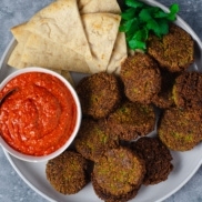 A hearty plate of plant-based falafel with romesco sauce that's sweet, tangy, and zippy,served with pita bread