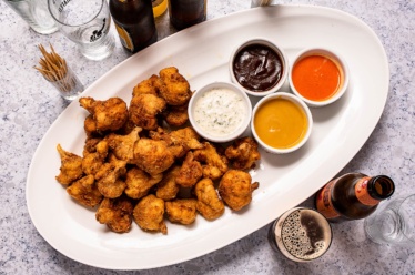 A tray of fried cauliflower "wings" for a plant-based superbowl appetizer with dipping sauces