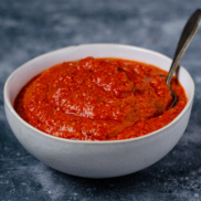 A bowl of lightly sweet and zippy romesco sauce with roasted red peppers and sundried tomatoes perfect for serving with falafel for a plant-based entree