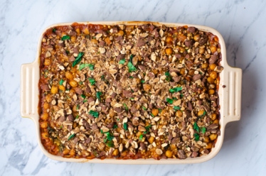 A casserole of chickpea and pearl couscous gratin flavored with curry inspired flavors and topped with cilantro and chopped almonds for a satisfying plant-based dinner idea