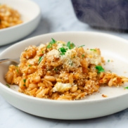 A plate of white bean and orzo gratin topped with seasoned breadcrumbs and herbs and flavored with mediterranean inspired flavorings for a delicious, plant-based dinner idea