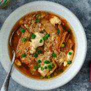 A bowl of kimchi and silken tofu soup that makes for a 10 minute, super-quick and easy vegan soup alternative for chicken noodle soup