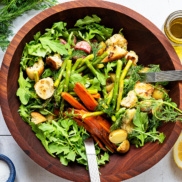 A big wood bowl of panzanella salad with Roasted Spring Vegetables of potato, asparagus, cucumber, and radish, topped with olive oil, lemon juice, salt, pepper, and fresh herbs like dill or mint