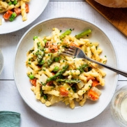A bowl of warm, bright, zesty, pasta primavera made from roasted spring vegetables of asparagus, potato, leek, radish and/ or fennel and tossed with a zesty, dairy-free, vegan cauliflower alfredo