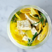 A jar of lemon-rosemary brined. dairy-free plant-based feta cheese made from tofu