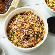 A classic multi-color coleslaw made plant-based ad vegan featurig green and purple cabbage, red bell pepper, shredded carrot, and a zesty dressing