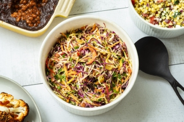 A classic multi-color coleslaw made plant-based ad vegan featurig green and purple cabbage, red bell pepper, shredded carrot, and a zesty dressing
