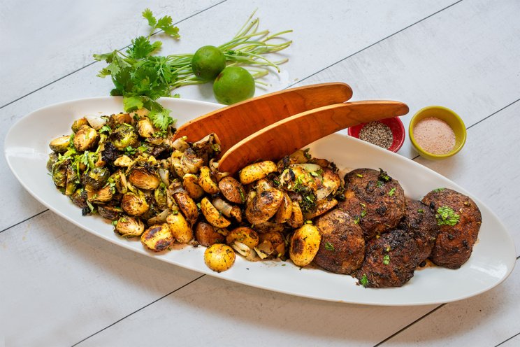 A sheet pan dinner of roasted Brussels sprouts and portabella mushrooms, topped with a chimichurri sauce